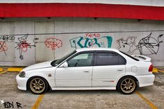 a white car parked in front of a graffiti covered wall