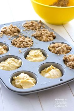 a muffin tin filled with cupcake batter next to a bowl of crumbs