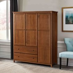 a bedroom with a blue chair and wooden armoire in front of a large window