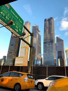 two taxi cabs are stopped at an intersection in front of the city skyline with skyscrapers