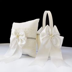 a white ring bearer and pillow with satin bows on it, sitting next to each other