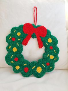 a crocheted christmas wreath hanging on a pillow