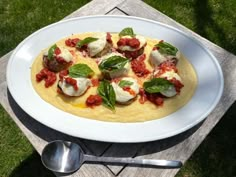 a white plate topped with food on top of a wooden table next to a spoon