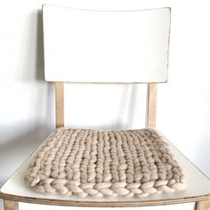 a chair with a cushion on top of it in front of a white wall and floor