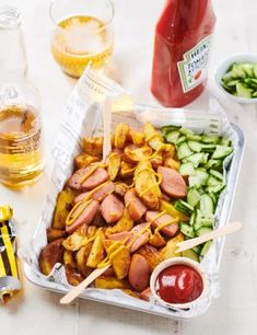 there are many different types of food in the trays on the table, including ketchup and pickles