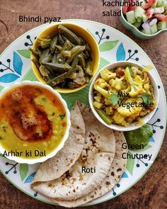 a plate filled with different types of food on top of a wooden table next to bowls of vegetables