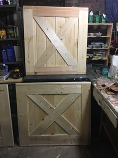 a wooden cabinet with sliding doors on the front in a workshop area next to other workbench and tools