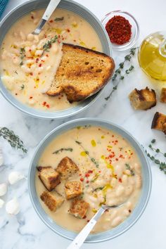 two bowls filled with soup and bread on top of a table