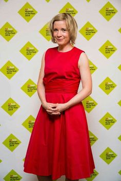 a woman in a red dress standing next to a green and white wall with yellow squares