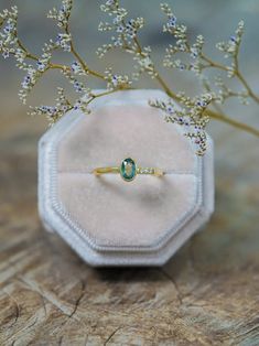 an engagement ring sitting on top of a wooden table next to a flower branch with white flowers