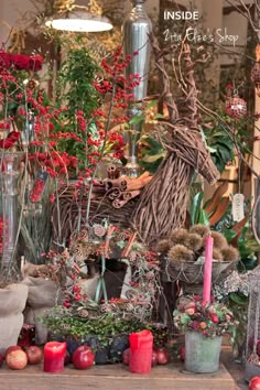 a table topped with lots of vases filled with flowers and plants next to candles