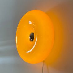 an orange object is hanging on the wall next to a light bulb that has a hole in it