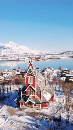 an aerial view of a red church in the middle of winter with snow on the ground