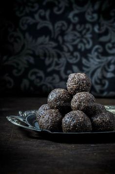 a pile of chocolate covered donuts sitting on top of a glass plate in front of a wall