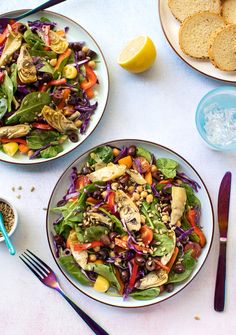 two plates filled with salad next to some bread