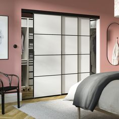 a bedroom with pink walls and white sliding doors in the middle, along with a black chair