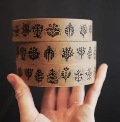 a person holding up three rolls of washi tape with trees on them in front of a black background