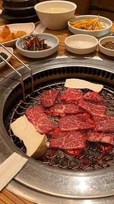 steaks and cheese are cooking on the grill in front of other plates with food