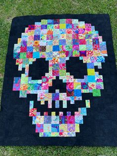 a patchwork quilt with a skull made out of different colored squares on the ground