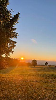 the sun is setting over an open field