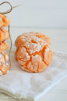 three powdered sugar cookies are on a white napkin and tied with twine, sitting next to each other