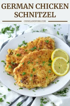 chicken schnitzel on a white plate with lemon wedges and parsley