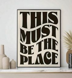 this must be the place art print in black and white on a shelf next to vases