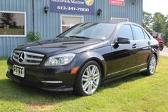 a black mercedes c - class parked in front of a building with cars behind it