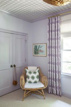 a wicker chair sits in the corner of a room with purple walls and curtains