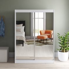 a room with a bed, chair and mirror on the wall next to a potted plant