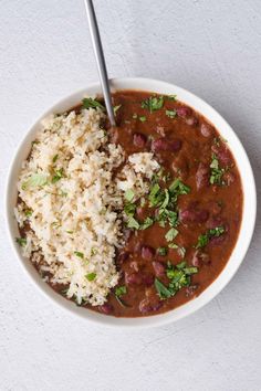 a white bowl filled with rice and beans next to a spoon on top of a table