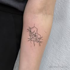 a black and white photo of a flower tattoo on the right arm, next to a woman's leg