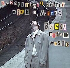 a man standing next to a train station with words all over him that spell out the word back ground music