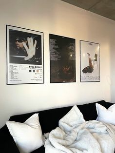 a black couch with white pillows and pictures on the wall