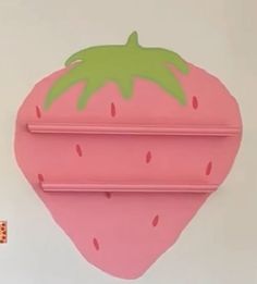 a pink strawberry shaped object hanging on the wall