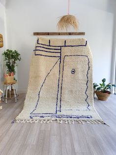 a white rug with blue lines and fringes hanging on a wooden rack in a room