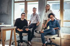 group of people sitting in an office smiling at the camera with their feet up on a desk