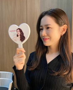 a woman holding up a heart shaped mirror