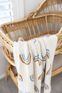 a wicker chair with a blanket on top of it in front of a window