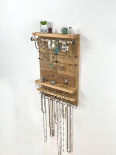 a wooden shelf with many necklaces hanging from it's sides and chains on the bottom