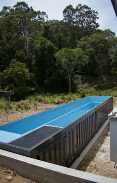 a large blue swimming pool in the middle of a field with lots of trees behind it