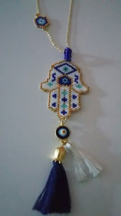 a beaded hamsa necklace with tassels and evil eye beads hanging from it