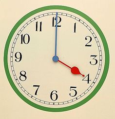 a green and white clock with red hands