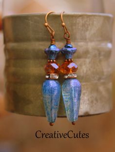 Rustic Copper dangles with beautiful blue & amber Czech glass beads & sparkly crystal copper rings...Uniquely Beautiful! Uniquely hand crafted with these quality materials: ~ Czech glass fire polished faceted beads ~ Crystal encrusted copper spacer rings ~ Antiqued copper findings & lead & nickel-free French style ear wires ~ Silicone earring backs to keep earrings securely in ears Measuring 2 inches from the top of the ear wires to the bottom of the beads, they're light weight & Blue Bohemian Crystal Drop Earrings, Bohemian Blue Crystal Drop Earrings, Handmade Blue Bohemian Crystal Earrings, Blue Teardrop Bohemian Crystal Earrings, Vintage Blue Dangle Beaded Earrings, Vintage Blue Beaded Drop Earrings, Blue Earrings With Dangling Beads, Unique Blue Earrings With Dangling Beads, Unique Blue Long Drop Earrings