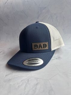 Celebrate your favorite Dad with the perfect gift! These leather patch hats are made with high quality leatherette and premium, adjustable snapback, 6 panel, structured trucker hats! Dad will love this hat! *Shown in photo: �→ Hat Color: Navy\Silver → Patch Color: Light Brown ►THE DETAILS: → Premium 6 Panel Trucker Snapback Hat → Fabric: Cotton-Poly/Nylon Mesh → Size: Adjustable Snapback One Size Fits Most → Leatherette Patch ►WASHING INSTRUCTIONS: → Wipe dirty areas only with a damp cloth → If n Dad Pregnancy Announcement, Gifts For Dad Birthday, Hat Fabric, Leather Patch Hat, Patch Hats, Birthday Gift For Dad, Patch Hat, Christmas Gift For Dad, Dad Birthday Gift