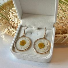 𝐑𝐄𝐀𝐋, 𝐏𝐑𝐄𝐒𝐒𝐄𝐃 𝐅𝐋𝐎𝐖𝐄𝐑𝐒 ✨    These earrings are made with real pressed flowers, perfectly preserved within resin. Their color and beauty will live on forever!       This is the perfect, 𝐭𝐡𝐨𝐮𝐠𝐡𝐭𝐟𝐮𝐥 gift for any plant lover, flower enthusiast, or unique jewelry girlie in your life.          𝐅𝐞𝐚𝐭𝐮𝐫𝐞𝐬: Real flowers preserved in crystal-clear resin.    Gold-plated hooks for a luxurious and durable finish.    Each pair is unique, showcasing the natural beauty of daisy White Earrings With Pressed Flowers As Gift, White Earrings With Pressed Flowers For Gift, Gift Pressed Flower Earrings, Birth Flower Earrings Gift, Gift Flower Earrings With Pressed Flowers, Dainty Round Earrings With Pressed Flowers, White Resin Jewelry With Birth Flower, White Resin Birth Flower Jewelry, Floral Earrings With Pressed Flowers For Mother's Day