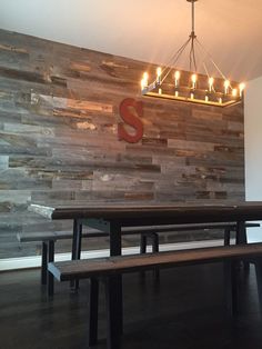 a wooden wall with lights hanging from it's sides and a bench in the foreground