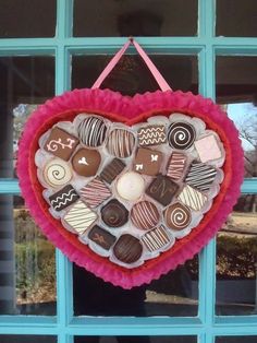 a heart shaped decoration made out of chocolates on a window sill with a blue frame