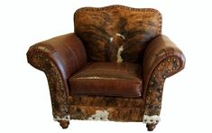 a brown and white cowhide chair with studded trim on the armrests