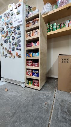 a white refrigerator freezer sitting inside of a kitchen next to a shelf filled with food